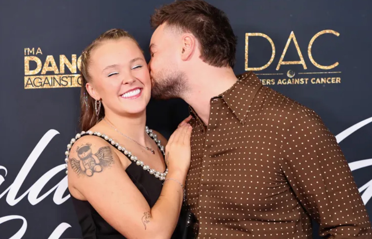 JoJo Siwa and Chris Hughes on red carpet at Beverly Hills charity gala – Siwa black gown, Hughes white trousers.
